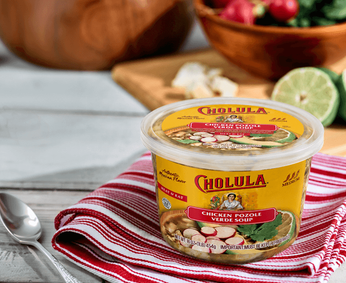 A Cholula chicken pozole verde soup container on a striped towel