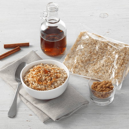 A bowl of oatmeal with maple syrup and brown sugar beside a bag of rolled oats