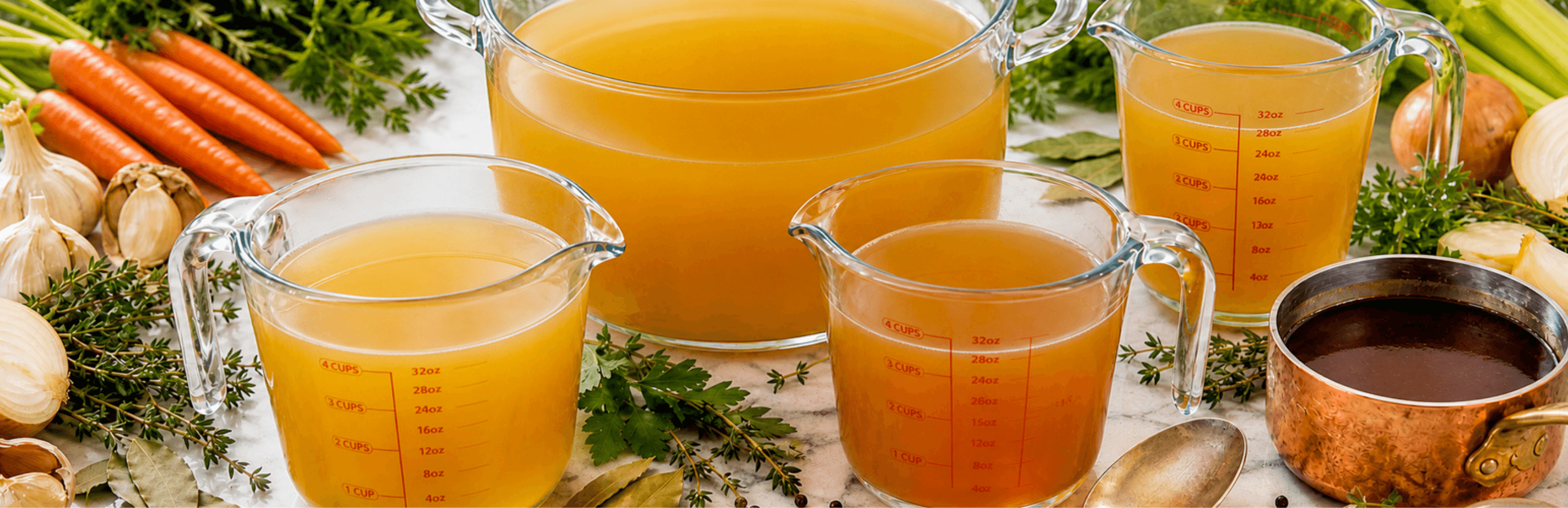 Demi-glace poured into a saucepan beside a jug of stock and a pot of broth