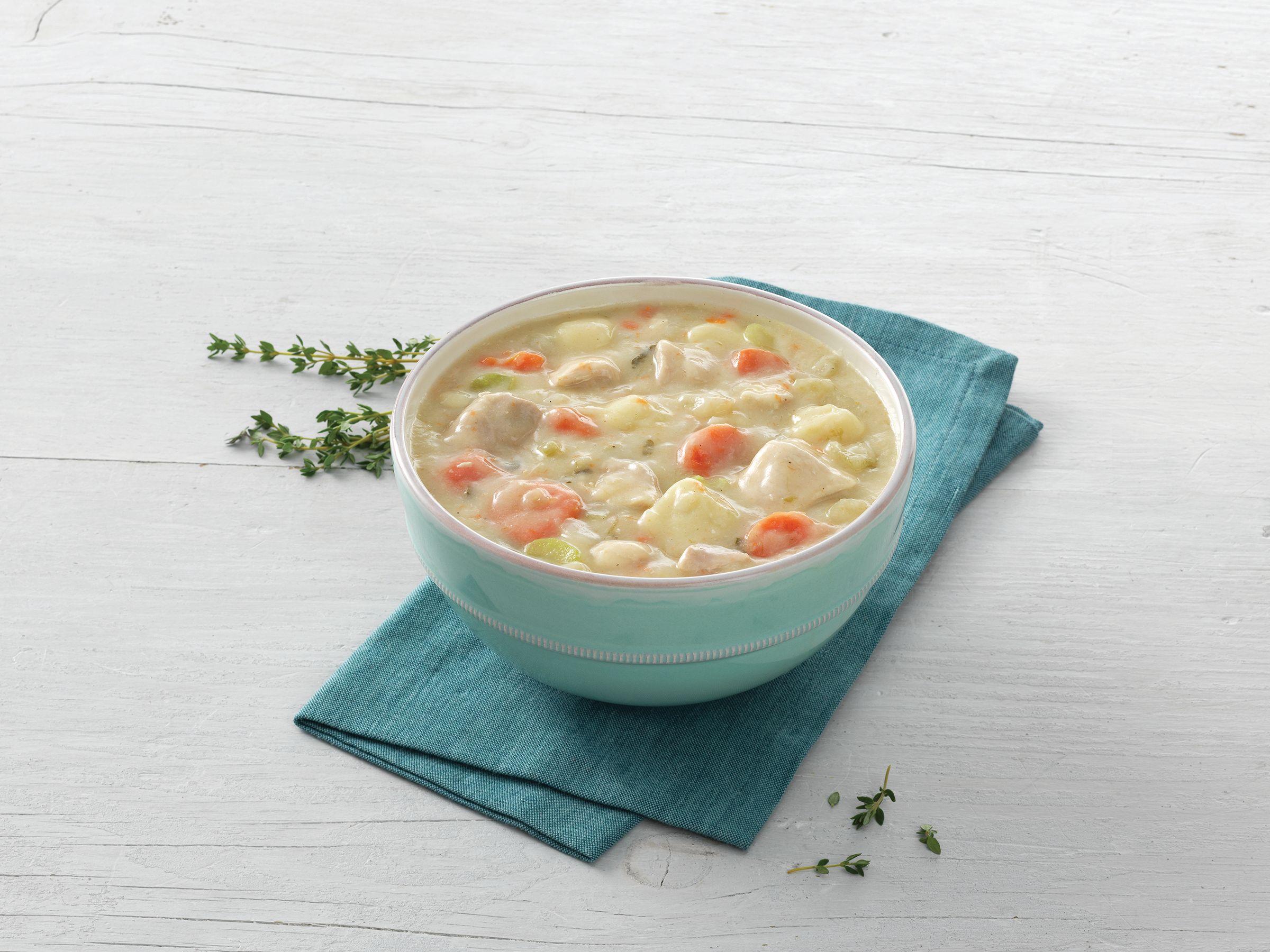 A bowl of Kettle Cuisine chicken and dumpling soup resting on a teal napkin