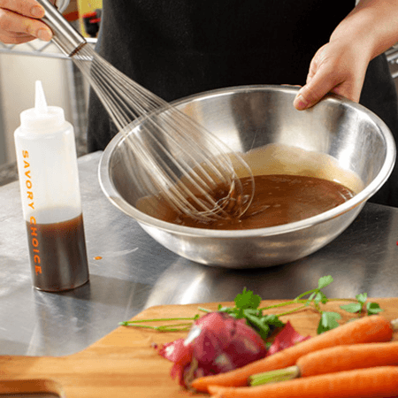 A cook whisking demi-glace in a mixing bowl beside a Savory Choice concentrate bottle