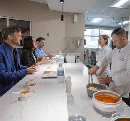Kettle Cuisine chefs presenting soup samples to retail customers across a tasting counter