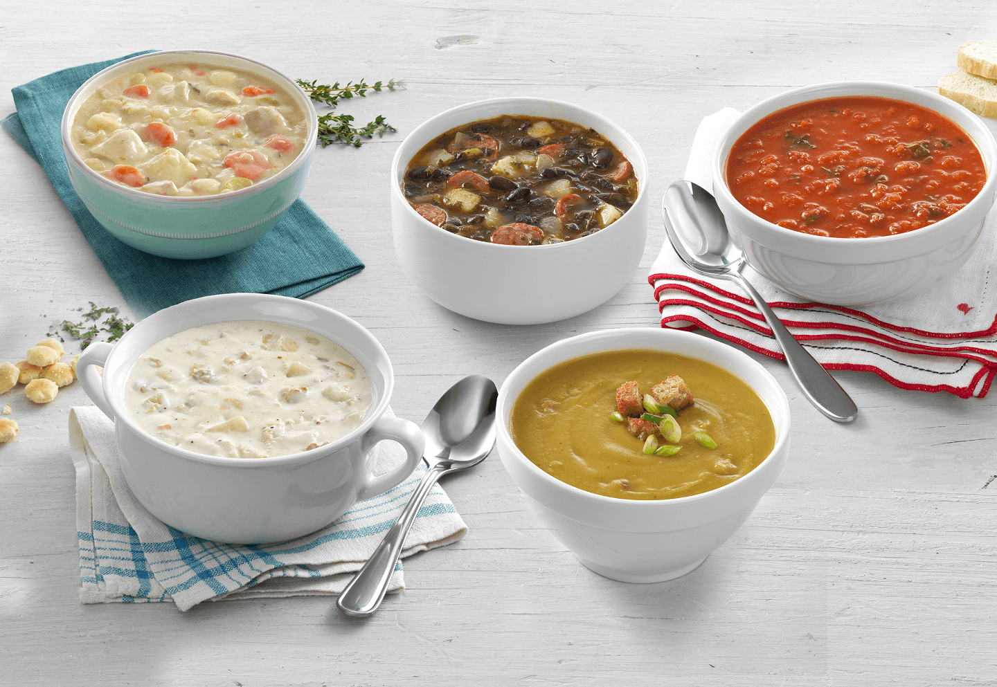 Five chef-crafted soups in bowls on a whitewashed table