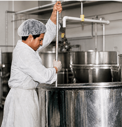 A Kettle Cuisine cook stirring a batch in a stainless steel kettle