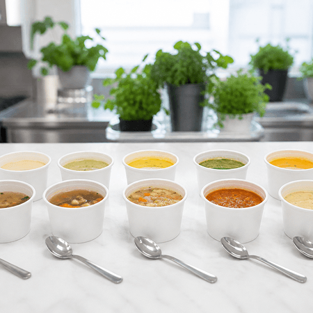 Cups of soup lined up for tasting along a marble counter in the culinary innovation kitchen