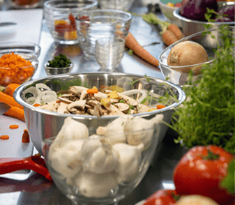 Mixing bowls of mushrooms, garlic and fresh vegetables staged across a prep table