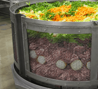 Shredded carrots and greens loaded into a large mesh cooking basket